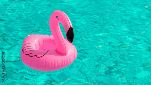 Summer time. Pink inflatable flamingo in pool water for summer beach background. Funny bird toy for kids. © Maksym