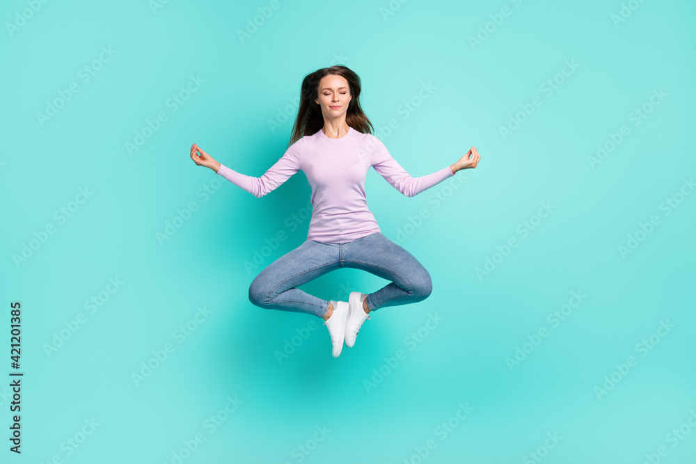 Full length body size view of attractive dreamy girl jumping sitting lotus pose meditating isolated over turquoise bright color background Full length body size view of attractive dreamy girl jumping sitting lotus pose meditating isolated over turquoise bright color background