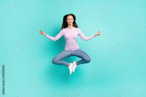 Full length body size view of attractive dreamy girl jumping sitting lotus pose meditating isolated over turquoise bright color background