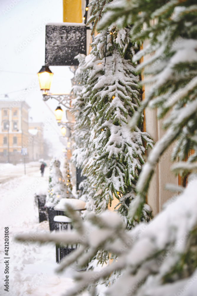 Aleksanterinkatu street during the strong snowstorm. Windows decorated with snow-covered spruce branches. The beautiful Christmas atmosphere in Helsinki, Finland.