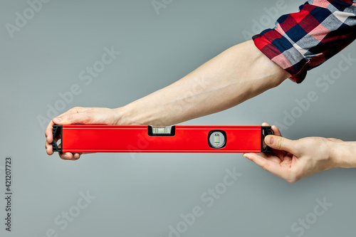Cropped Male Hands Holding Red Spirit Level For Carpentry