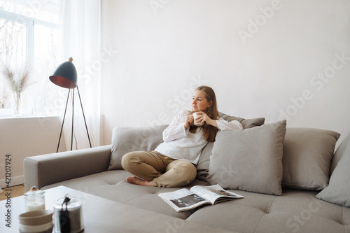 Young woman relaxing on the couch with hot beverage at home.