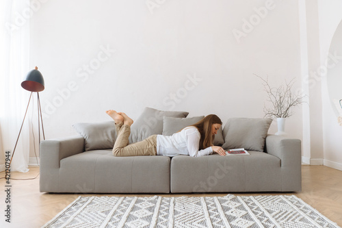 Young woman reading on the couch at home.