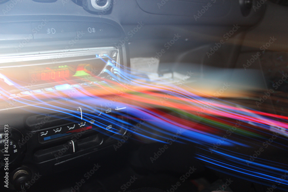 Abstract background of music coming out of the car stereo forming lights. Long exposure effect over car stereo radio player.