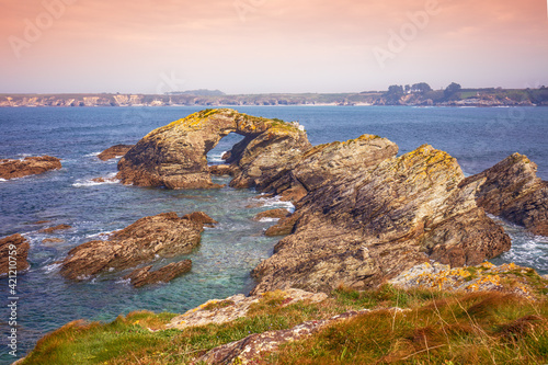 Seascape with the rocky shore in spring. View of Ria de Ribadeo del Eo bay. Rock with the natural arch. Ribadeo, Spain photo