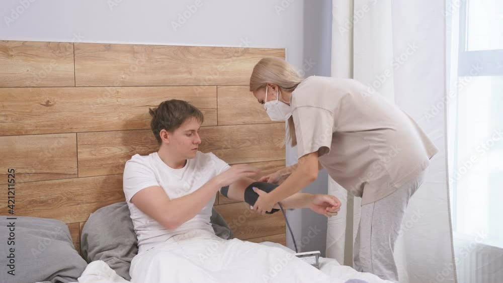 Worried wife take care his sick husband checking blood pressure, people must be wearing medical mask protecting from coronavirus(covid-19) pandemic, quarantined