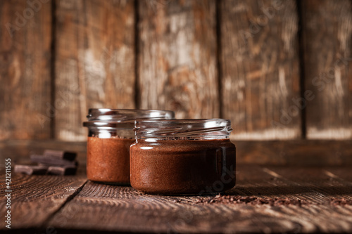 Homemade dark chocolate mousse in rural jars on rustic wood table