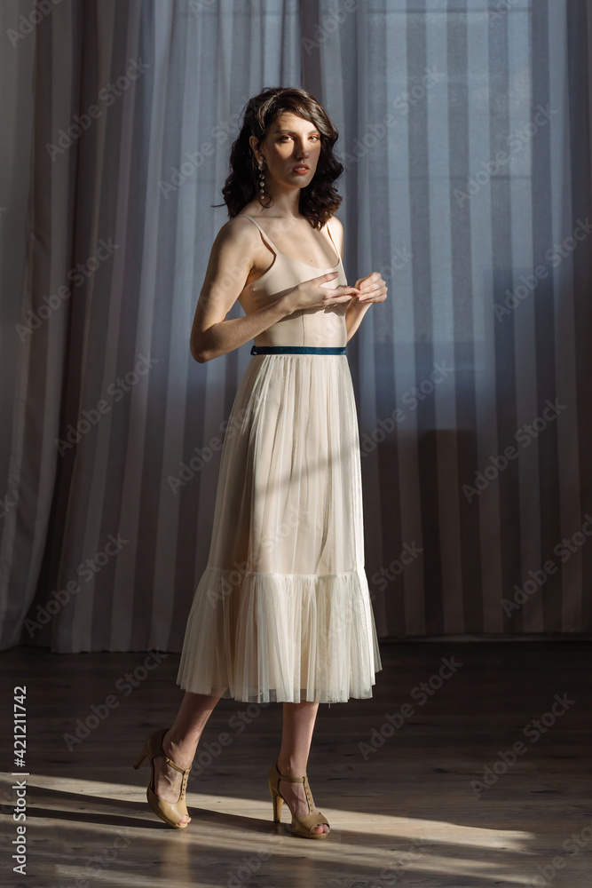 Cute young girl stands in the studio on the background of curtains. A stern look straight into the camera. Cute young girl stands in the studio on the background of curtains. A stern look straight into the camera.