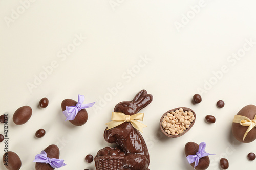 Flat lay composition with chocolate Easter bunny, eggs and candies on light background. Space for text
