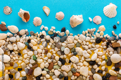 Sea light pebbles and shells on a blue and yellow background, vacation on the sea or ocean, background like sand with water