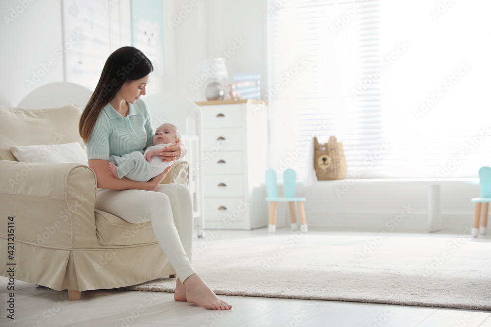 Young woman with her cute baby at home, space for text Young woman with her cute baby at home, space for text