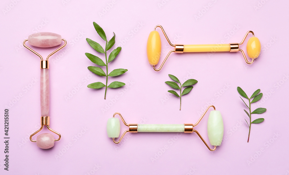 Natural face rollers and leaves on pink background, flat lay Natural face rollers and leaves on pink background, flat lay