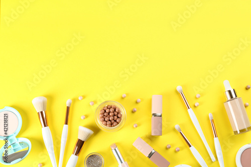 Flat lay composition with makeup brushes on yellow background, space for text