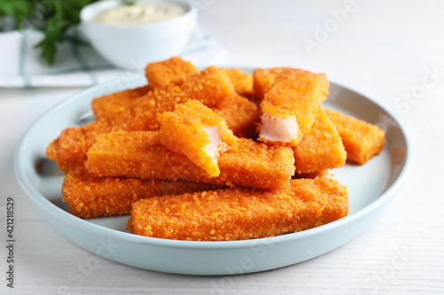 Fresh breaded fish fingers served on white table