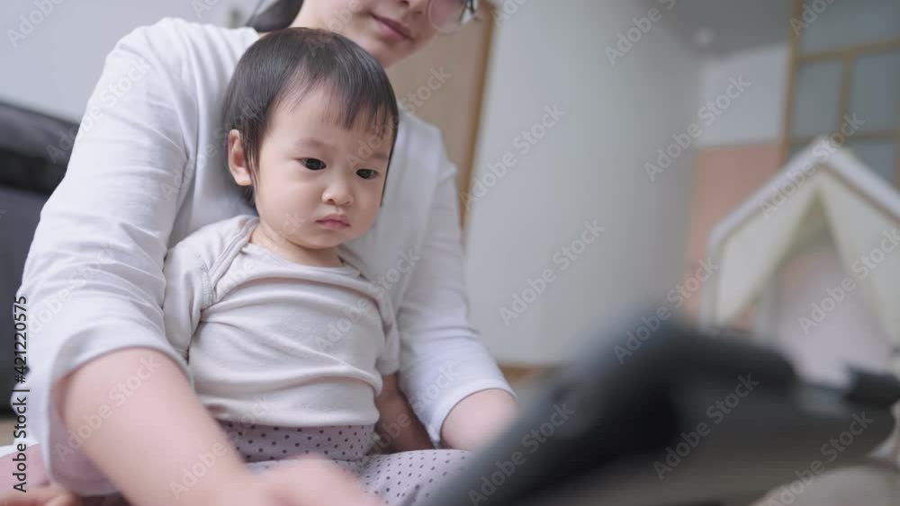 Adorable preschooler on mother lap watching still on tablet screen with young asian mother at home, Coronavirus COVID-19 quarantine, distance education online learning lesson concept, stay safe home Adorable preschooler on mother lap watching still on tablet screen with young asian mother at home, Coronavirus COVID-19 quarantine, distance education online learning lesson concept, stay safe home