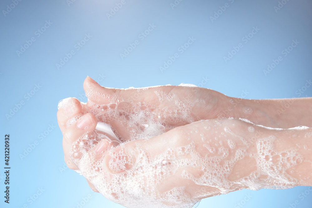 Woman hands in soapsuds, on blue background close-up. Woman hands in soapsuds, on blue background close-up.