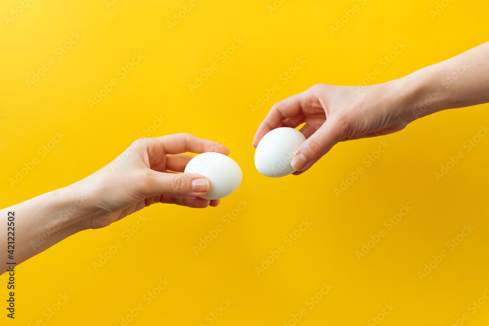 Woman hands holding Easter eggs for knocking on yellow background. Easter celebration or creative concept. Adam creation Woman hands holding Easter eggs for knocking on yellow background. Easter celebration or creative concept. Adam creation