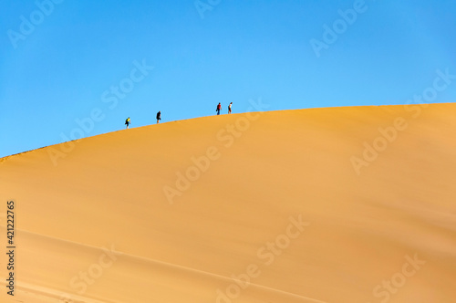 Beautiful Singing Dunes (barkhan) with silhouettes of unrecognisable tourists at the sunset at Altyn-Emel National Park in the desert in Kazakhstan