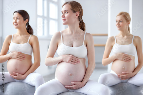 young pregnant women sitting on fitness ball, going in for sports. Pilates for expectant mothers.