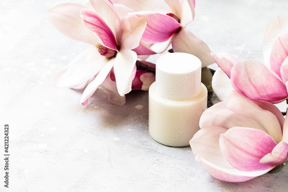 Cosmetics SPA branding mock-up. White cosmetic bottle containers with pink magnolia flowers on gray background Natural organic beauty product concept Cosmetics SPA branding mock-up. White cosmetic bottle containers with pink magnolia flowers on gray background Natural organic beauty product concept