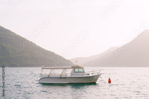 White motor boat with sun awning and cockpit in the middle of the Bay of Kotor. © Nadtochiy