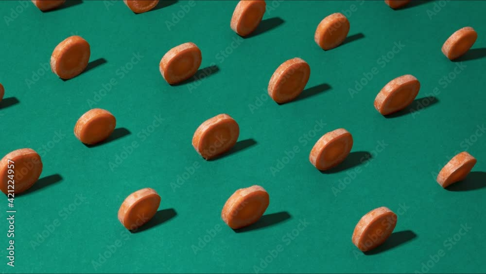 close up of rotating fresh raw carrot slices on green background, stop motion animation close up of rotating fresh raw carrot slices on green background, stop motion animation