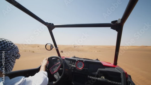 Young woman driving sand buggy on the sand dunes. Woman driving offroad vehicle in desert near Dubai