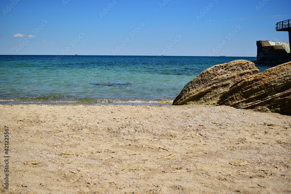 A picturesque seascape overlooking the blue sea, rocks and stones on a bright sunny day. on the beach. Wonderful view on the coast. Bright sun, blue sea. Vivid summer ambience, vacation, tourism