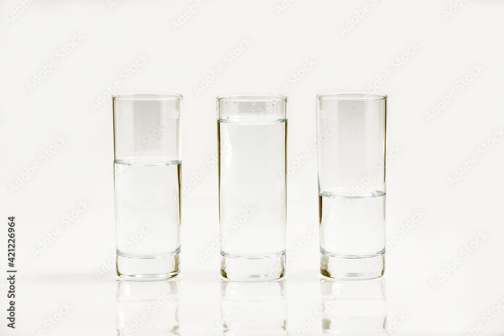Water in three glasses - different level, isolated over a white background - three plastic bottles of water Water in three glasses - different level, isolated over a white background - three plastic bottles of water