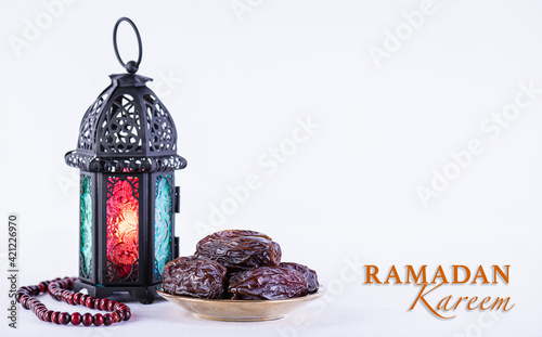 Ramadan food and drinks concept. Ramadan arabian lamp, wood rosary, and dates fruit on white background. photo