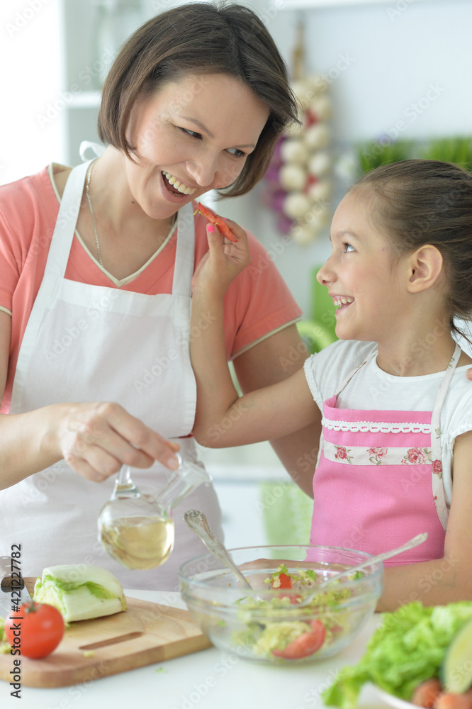 girl with her mother cooking together at kitchen table girl with her mother cooking together at kitchen table