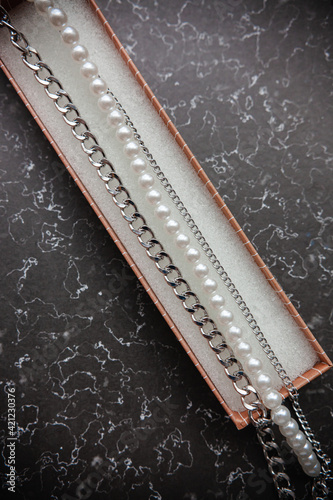 pearl jewelry and chains for girls and red tulips on a marble background