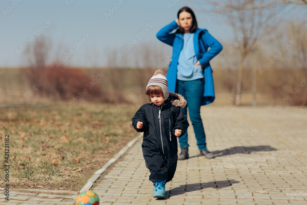 Fototapeta premium Stressed Mother Supervising Child Playing Outdoors