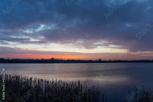 View of a calm lake and clouds after sunset
