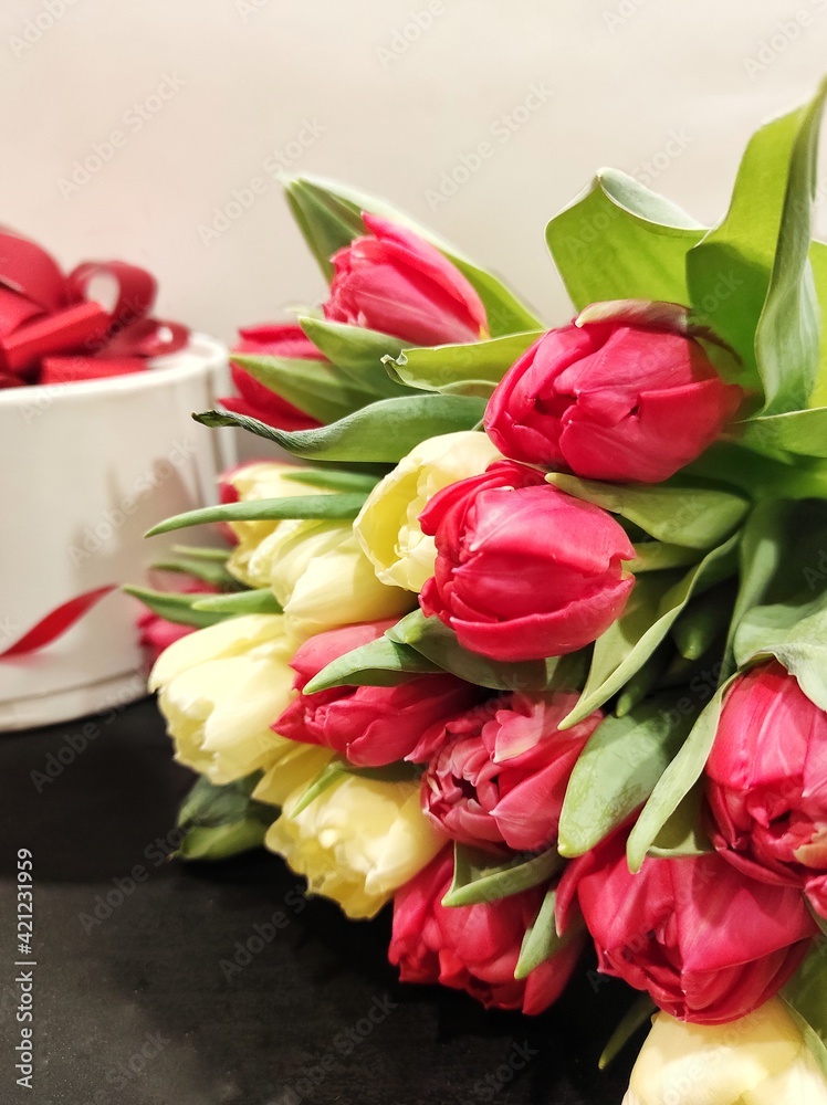 a bouquet of red and yellow tulips flowers next to a beautiful box close-up