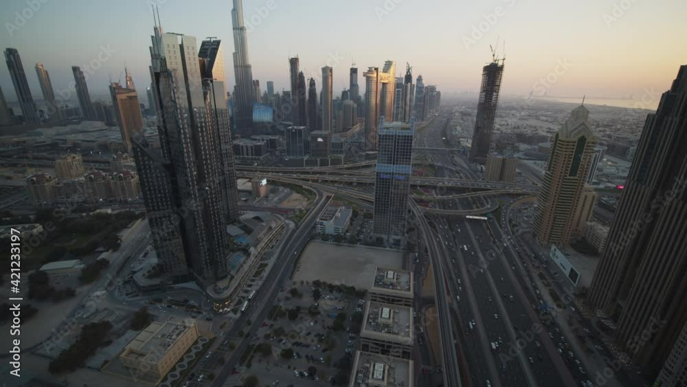 Slow tilt view of metropolitan Dubai city center with tall skyscrapers and busy multi lane highway traffic