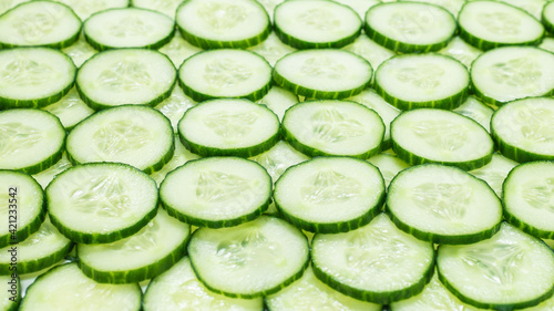 Fresh green slices of cucumber as background.