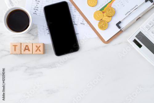 Top view of calculating and paying tax with smart phone on white table.