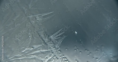 Abstract extreme close up macroscopic shot of water crystallizing and freezing on a translucent surface.