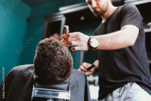 Close-up professional barber doing hair cut