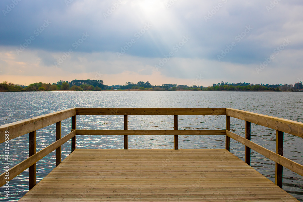 Lagoa da Vela, Portugal. View of lagoon and distant land from empty wooden pier in the morning light Lagoa da Vela, Portugal. View of lagoon and distant land from empty wooden pier in the morning light