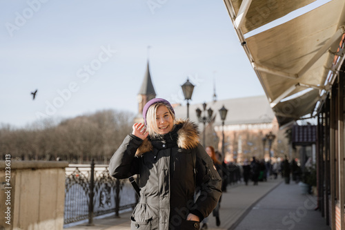 in the middle of the street a happy girl straightens her hair, in a purple hat, in a warm jacket