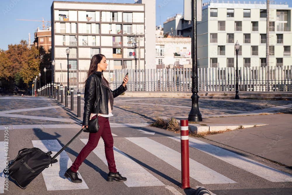 woman with suitcase walking and consulting phone