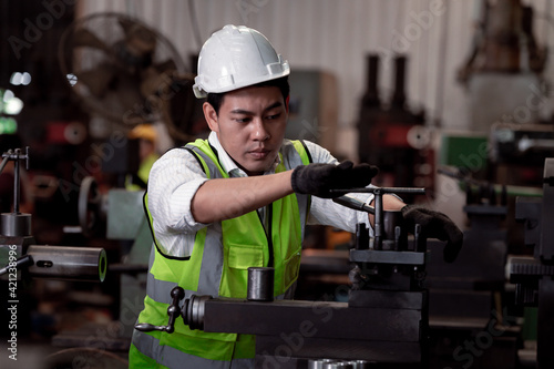 Industry engineer wearing safety uniform control operating lathe grinding machine working in industry factory.