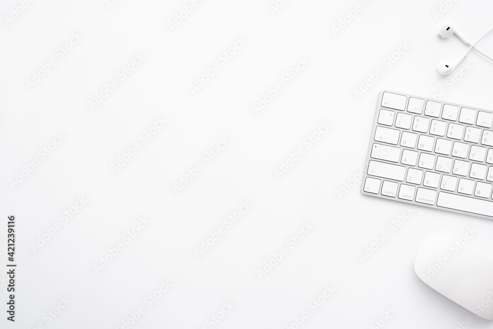 White minimal office desk table with computer keyboard, mouse and earphones. Top view with copy space, flat lay. White minimal office desk table with computer keyboard, mouse and earphones. Top view with copy space, flat lay.