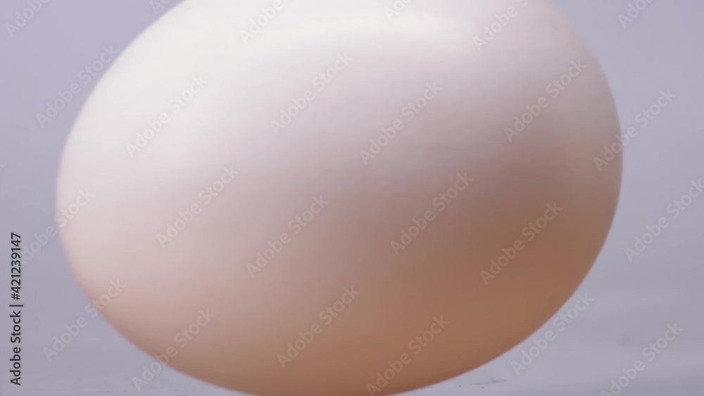White chicken egg spinning on a white background or white table. Nutrition White chicken egg spinning on a white background or white table. Nutrition