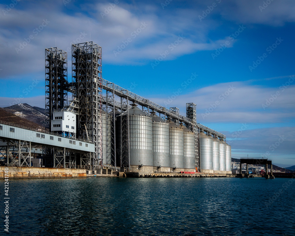 Grain storage tanks in the port next to the sea with a blue sky Grain storage tanks in the port next to the sea with a blue sky