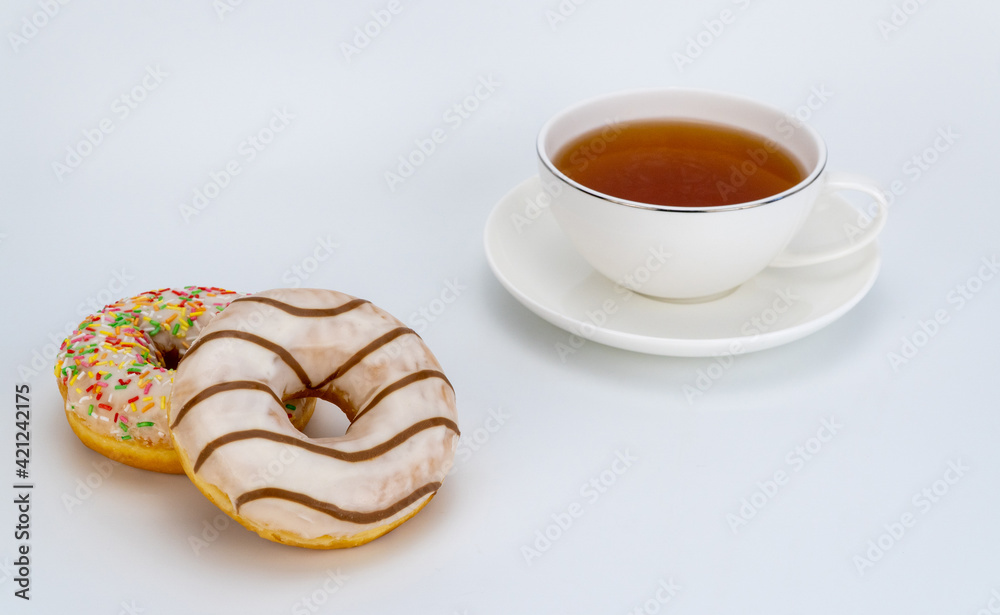 sweet donuts and a cup of tea on a white background. selective focus. sweet donuts and a cup of tea on a white background. selective focus.