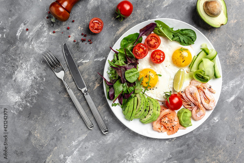 Ketogenic breakfast. Keto low carb salmon, boiled shrimps, prawns, fried eggs, fresh salad, tomatoes, cucumbers and avocado. top view. Low carb diet concept. high fat diet
