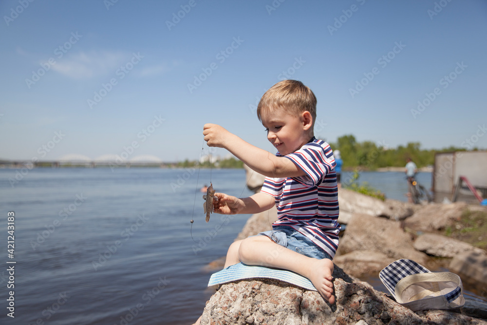 The little boy on the riverbank is fishing The little boy on the riverbank is fishing